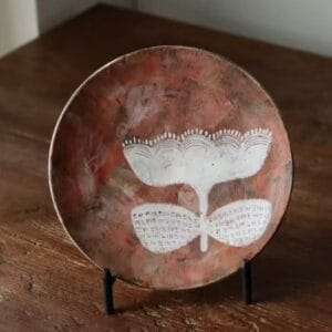 Handmade wabi sabi rustic ceramic floral plate displayed on a metal stand