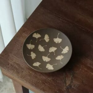 Vintage minimalist style ginkgo leaf ceramic plate displayed on a dark wooden table