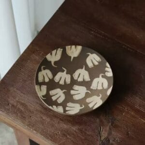 Vintage folk art style handpainted ceramic bird plate on a dark wooden background