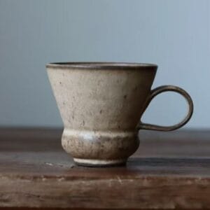 Side view of an artisanal ceramic flared cup with a vintage pedestal base