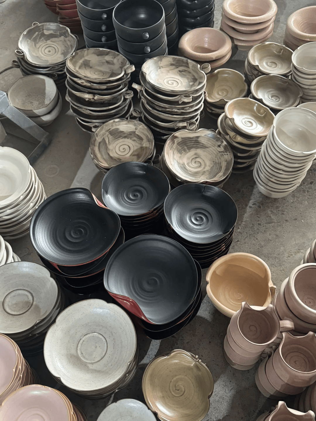 Rows of mass produced plates representing handmade vs factory ceramics differences.